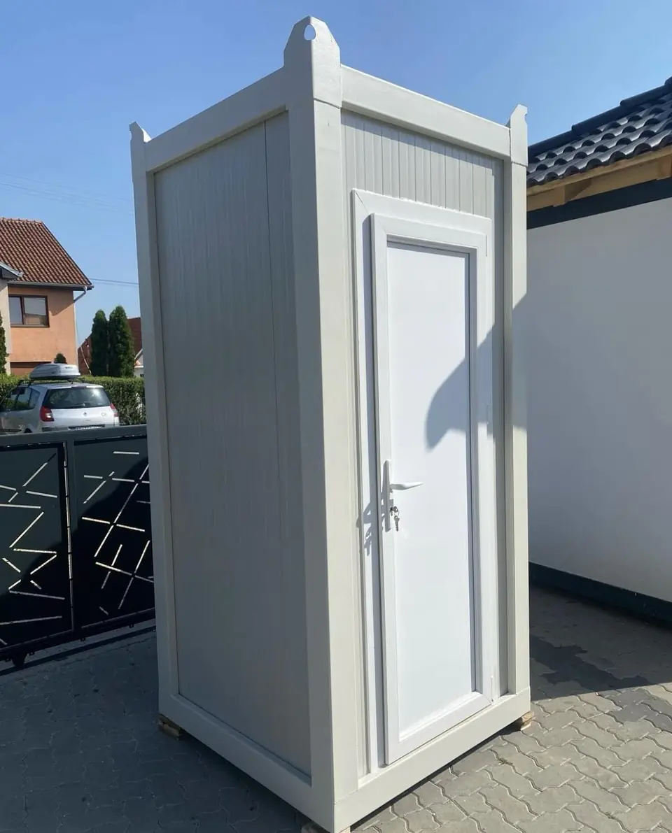 White deluxe flushing restroom cabin beside a fence