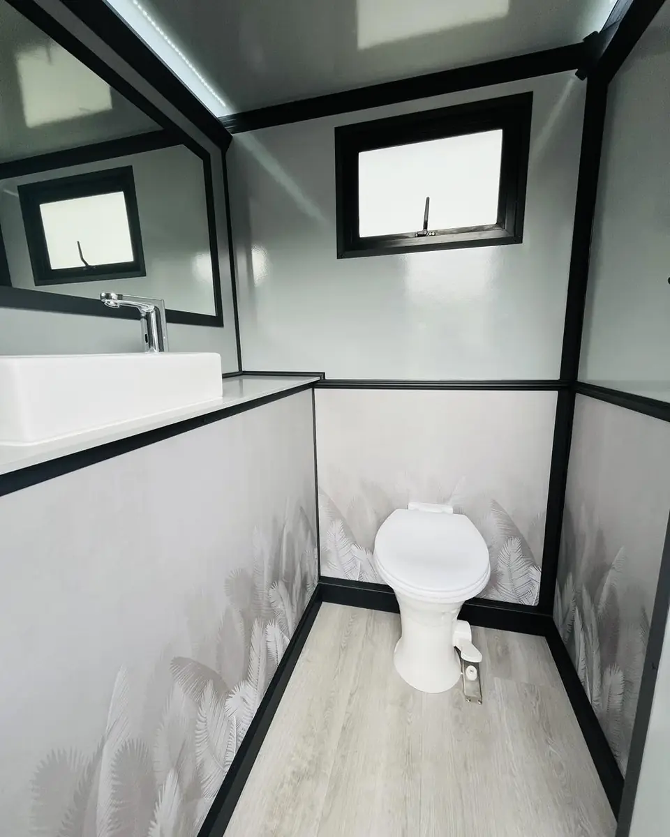 Flush toilet inside a restroom trailer with a window