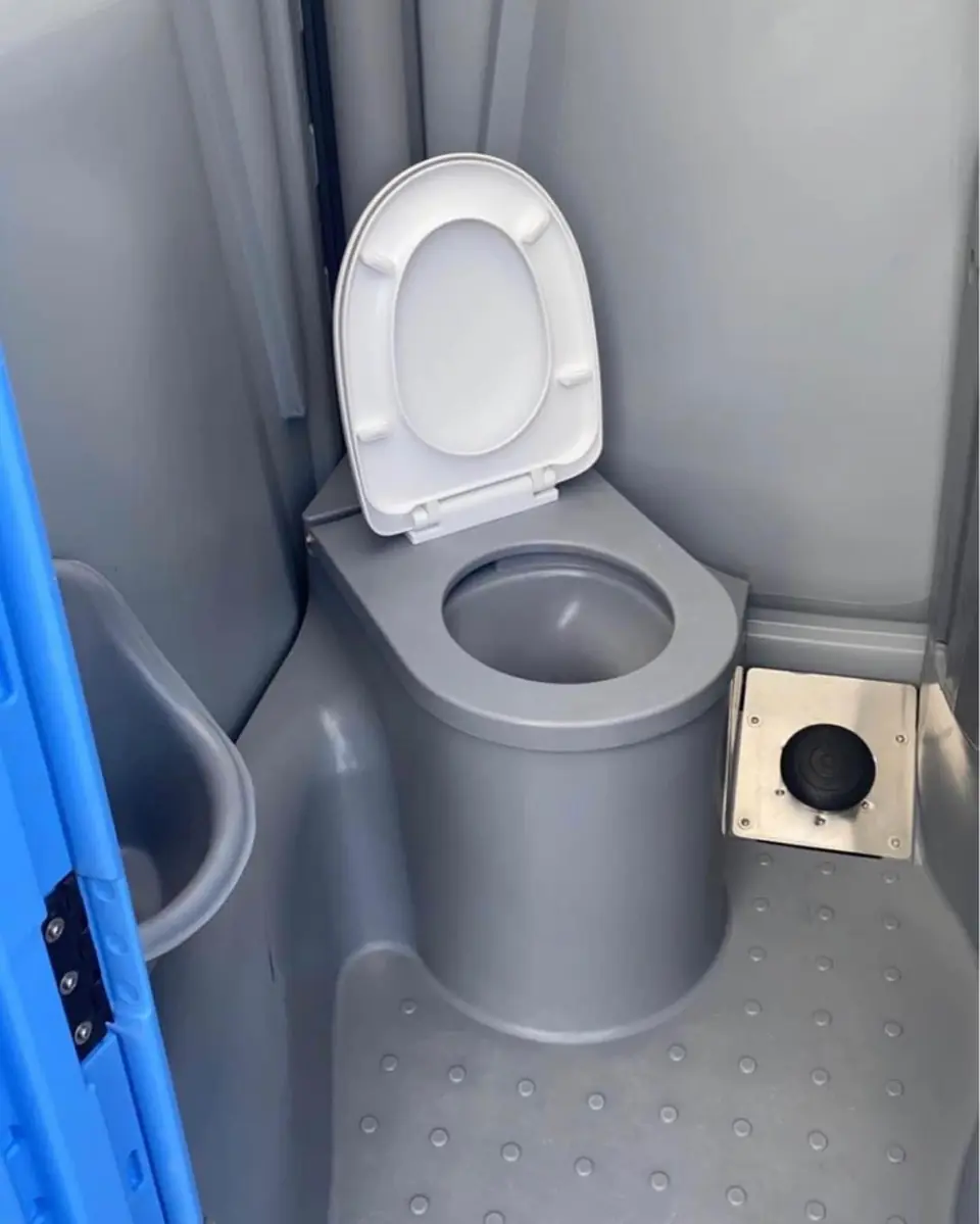 Inside a standard porta potty showing the toilet seat and toilet paper holder